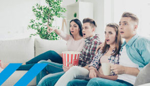 Familie sitzt aufregt mit Popcorn auf dem Sofa